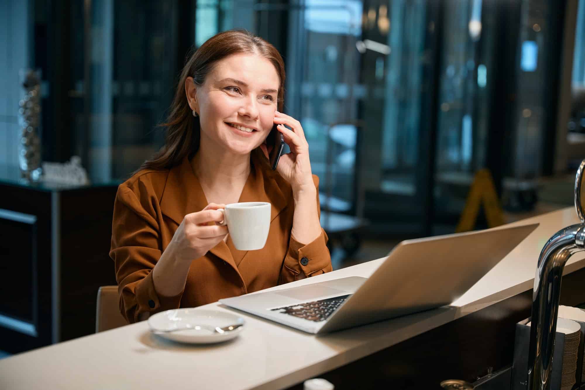 Contented lady talking on phone with coffee cup in hand